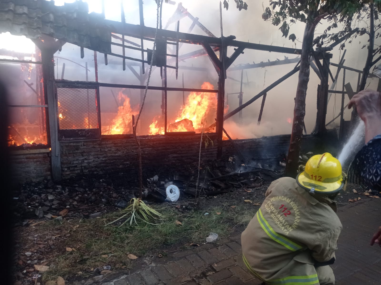 SIGAP : Petugas berusaha memadamkan api. Rumah warga di Jalan Lakarsantri, Surabaya, ini terbakar, pada Kamis (25/9).(IST/RADAR SURABAYA)