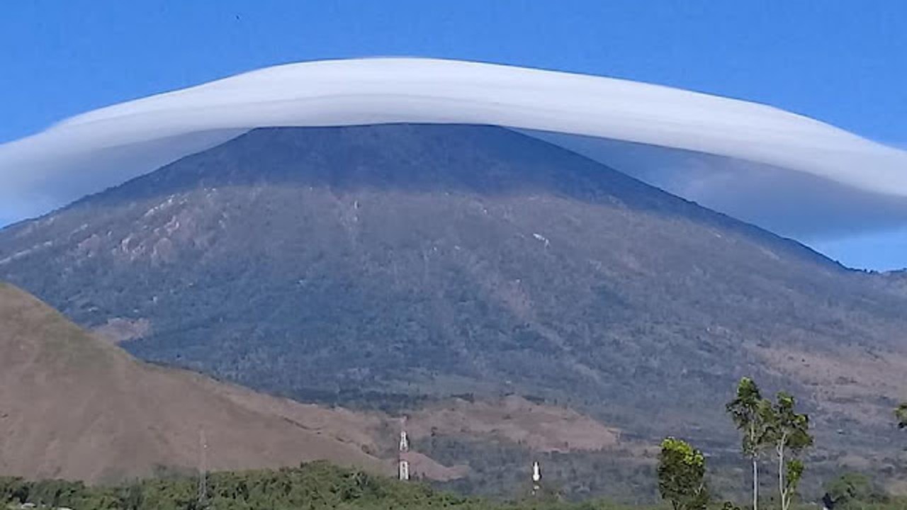 Awan lentikularis berbentuk seperti topi terlihat menutupi puncak Gunung Rinjani, fenomena langka yang terbentuk akibat arus angin kuat melewati puncak gunung.