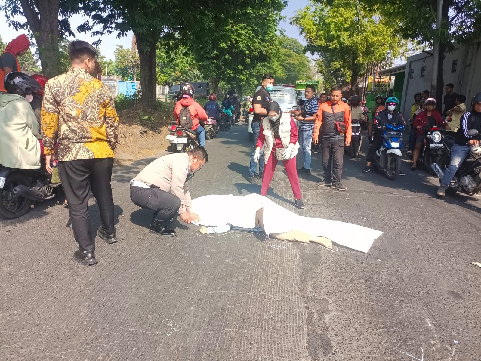 EVAKUASI: Petugas saat mengevakuasi jasad pengendara motor perempuan yang meninggal usai terlindas truk di Jalan Pakal, Surabaya.(IST/RADAR SURABAYA)