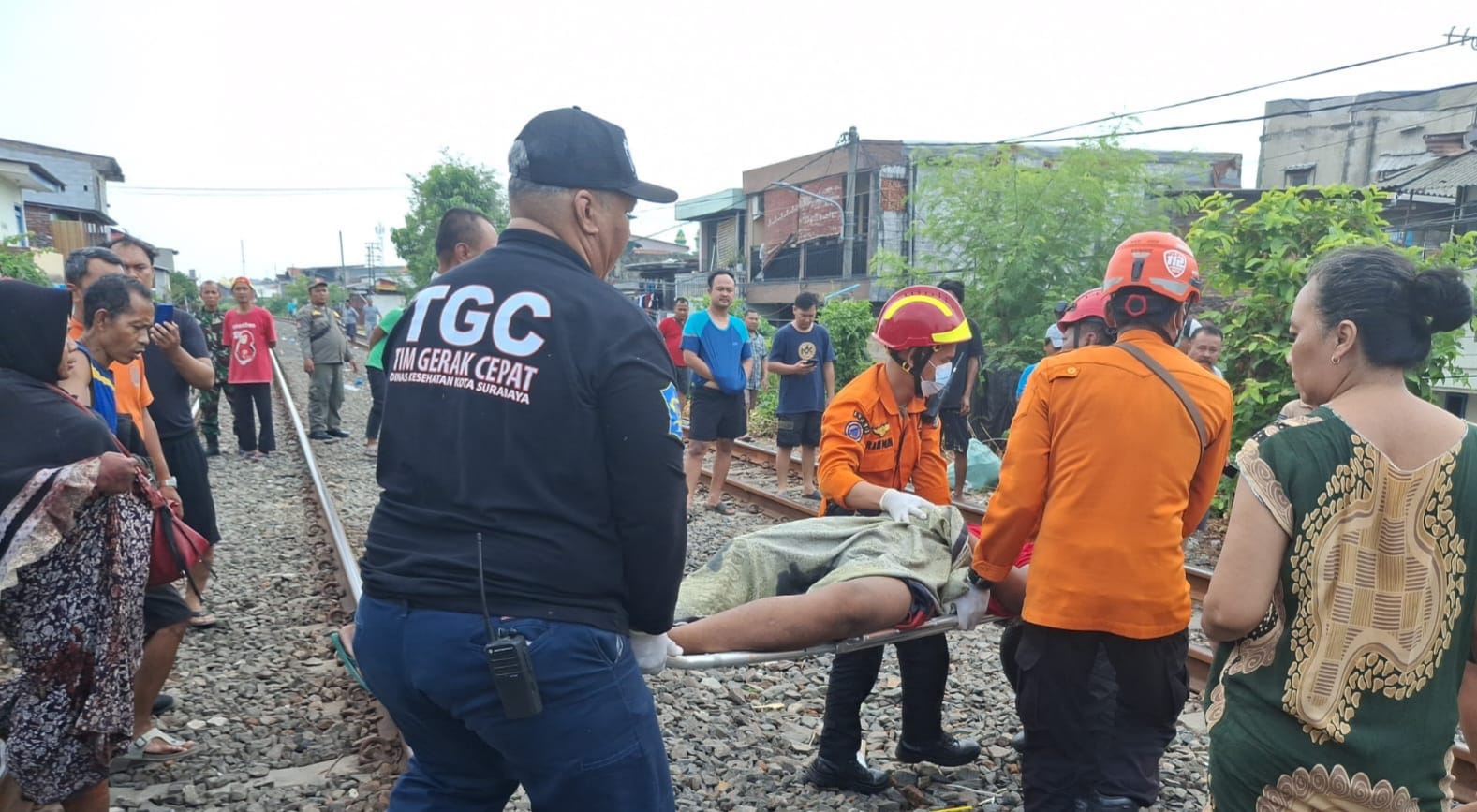 DIEVAKUASI : Petugas menggotong korban Sugiyanto untuk dibawa ke ambulans usai tertabrak KA di perlintasan Jalan Mustika Baru, Surabaya, Jumat (10/10).(IST/RADAR SURABAYA)