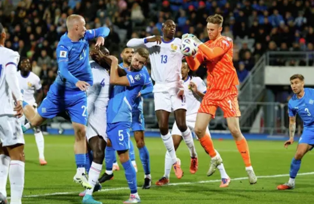 Kiper Islandia Elias Rafn Olafsson menguasai bola di depan pemain Prancis Jean-Philippe Mateta, tengah, saat pertandingan kualifikasi grup D Piala Dunia 2026 antara Islandia dan Prancis di Reykjavik.