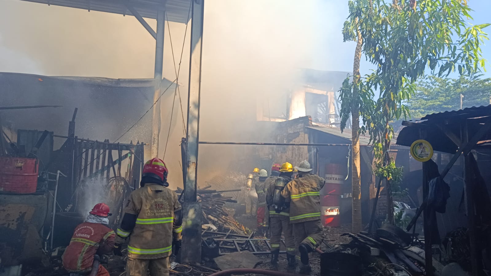 BERASAP: Petugas DPKP Surabaya melakukan pemadaman di bengkel sekaligus mess sopir di Jalan Tembok Gede, Surabaya. (IST/RADAR SURABAYA)