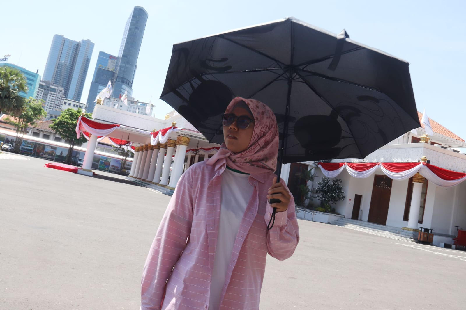 BERLINDUNG: Saking panasnya warga Surabaya menggunakan payung untuk menghindari dehidrasi.