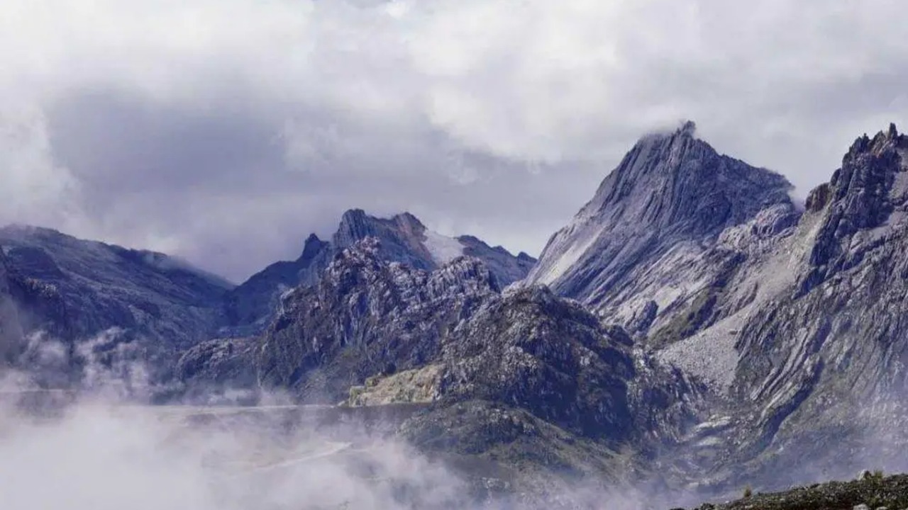 Puncak Pegunungan Jayawijaya di Papua yang diselimuti kabut tipis, menyisakan sedikit lapisan es abadi yang kini kian menipis akibat perubahan iklim.