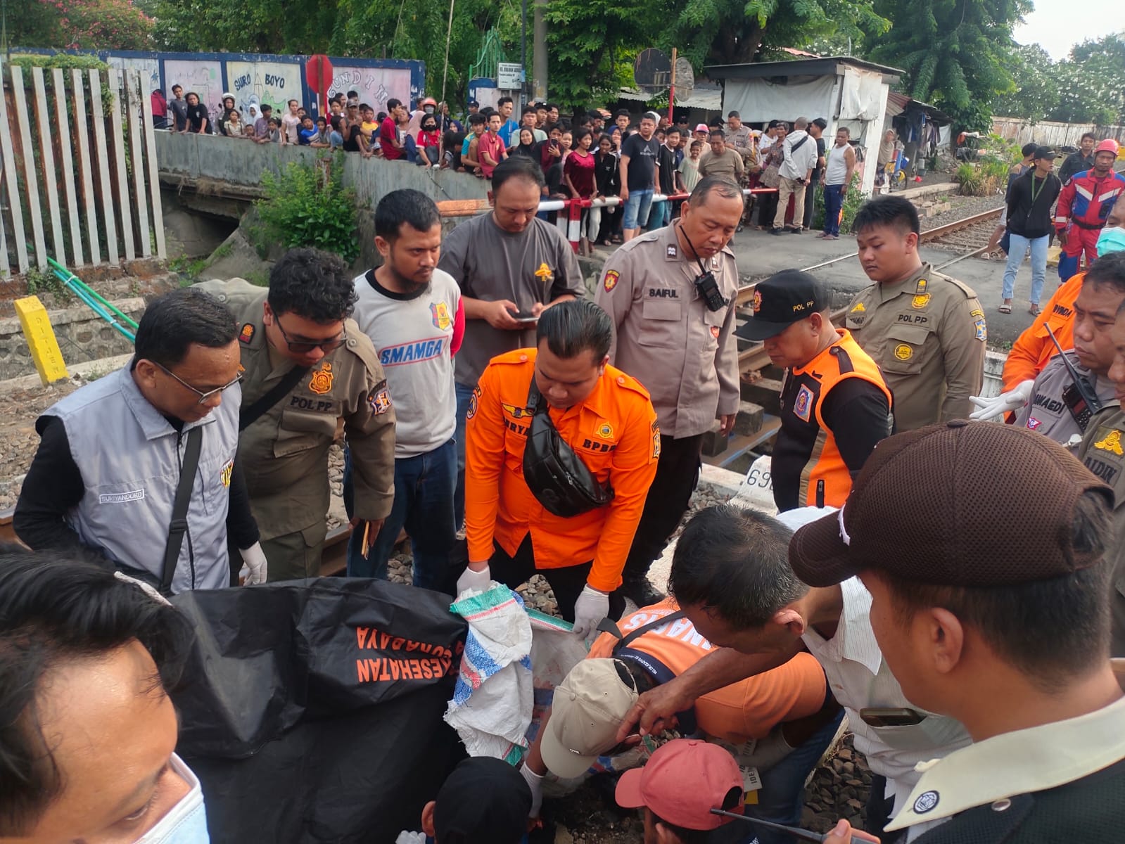 EVAKUASI : Petugas gabungan mengevakuasi Isan pengendara motor yang meninggal dunia tertabrak KA Arjonegoro di perlintasan Jalan Margorukun, Bubutan Surabaya, Sabtu (25/10).(IST/RADAR SURABAYA)