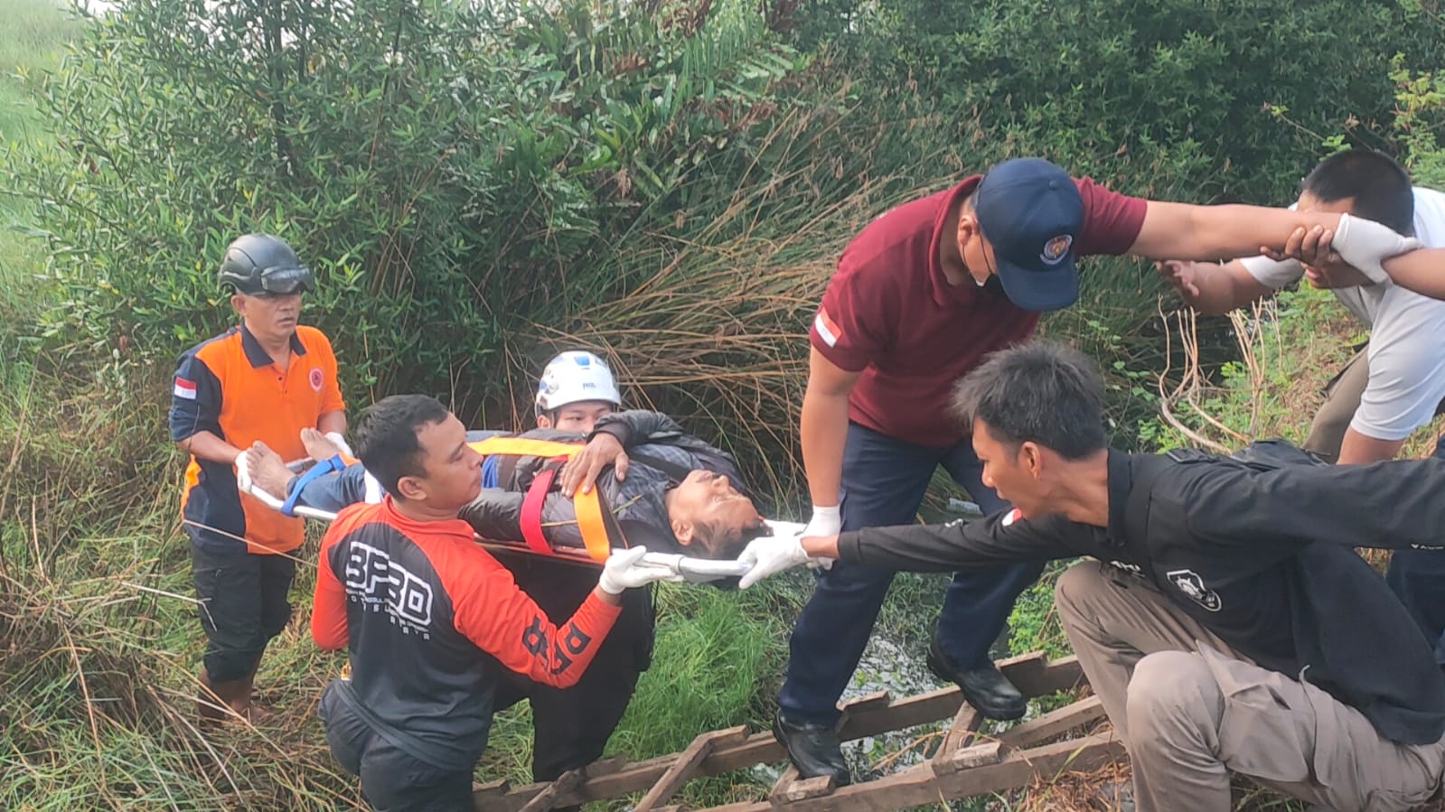 GOTONG ROYONG: Korban saat dievakuasi dari sungai di Jalan Jawar, Pakal, Surabaya. Pengendara motor ini mengalami patah tulang.(IST/RADAR SURABAYA)