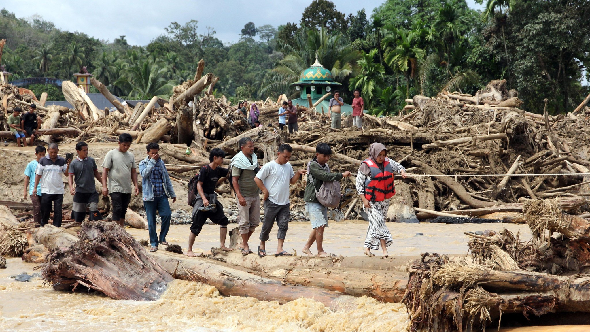 Warga melintas di kawasan Tapanuli Selatan, Sumatera Utara, yang dilanda banjir dahsyat. (IST)
