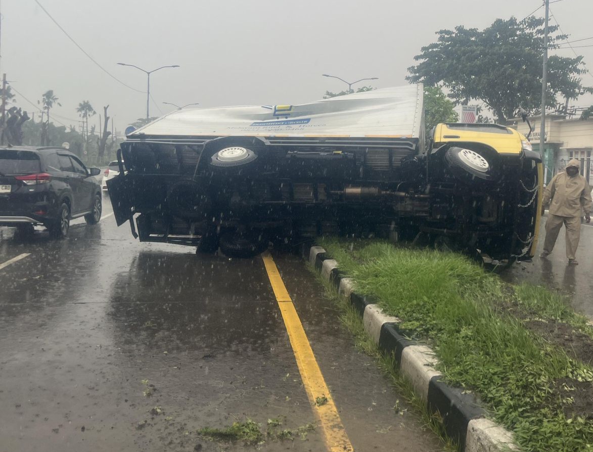 EVAKUASI: Truk boks yang terguling di Jalan Kedung Cowek, Surabaya, saat dievakuasi DPKP Surabaya. (IST/RADAR SURABAYA)