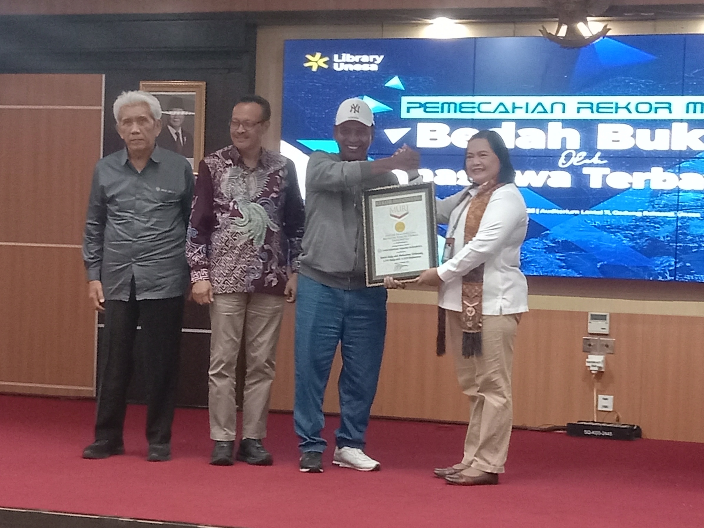Rektor Unesa Prof Nurhasan saat menerima penghargaan dari MURI yang diberikan oleh Sri Widayanti sebagai kampus yang mereview 11.078 buku mahasiswa baru, Selasa (9/12)