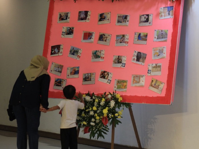 BERBAGI: Seorang ibu mengajak buah hatinya melihat pameran tentang cerita anak ODHIV yang dituangkan dalam sebuah foto dan dipamerkan di Balai Pemuda Surabaya.