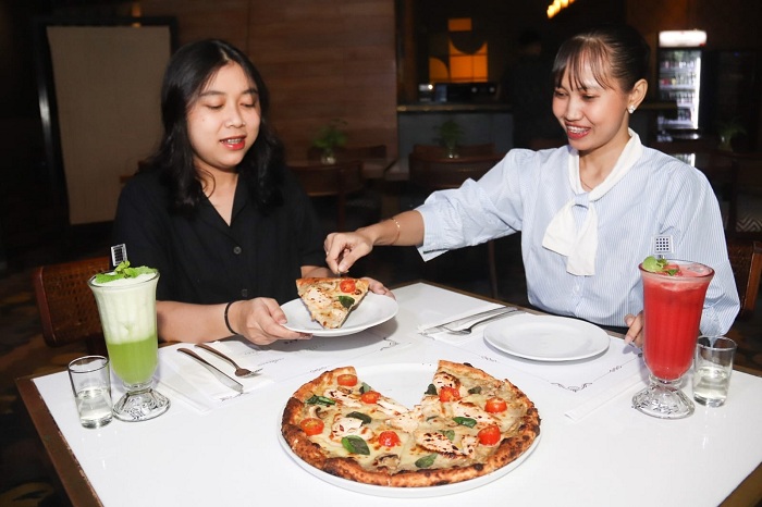 PIZZA KALKUN: Verren Agnes (kanan) dan rekannya menikmati sajian kreasi pizza dengan toping daging kalkun, salah satu menu yang disajikan ketika Natal, di Hotel Java Paragon Surabaya, Senin (15/12).