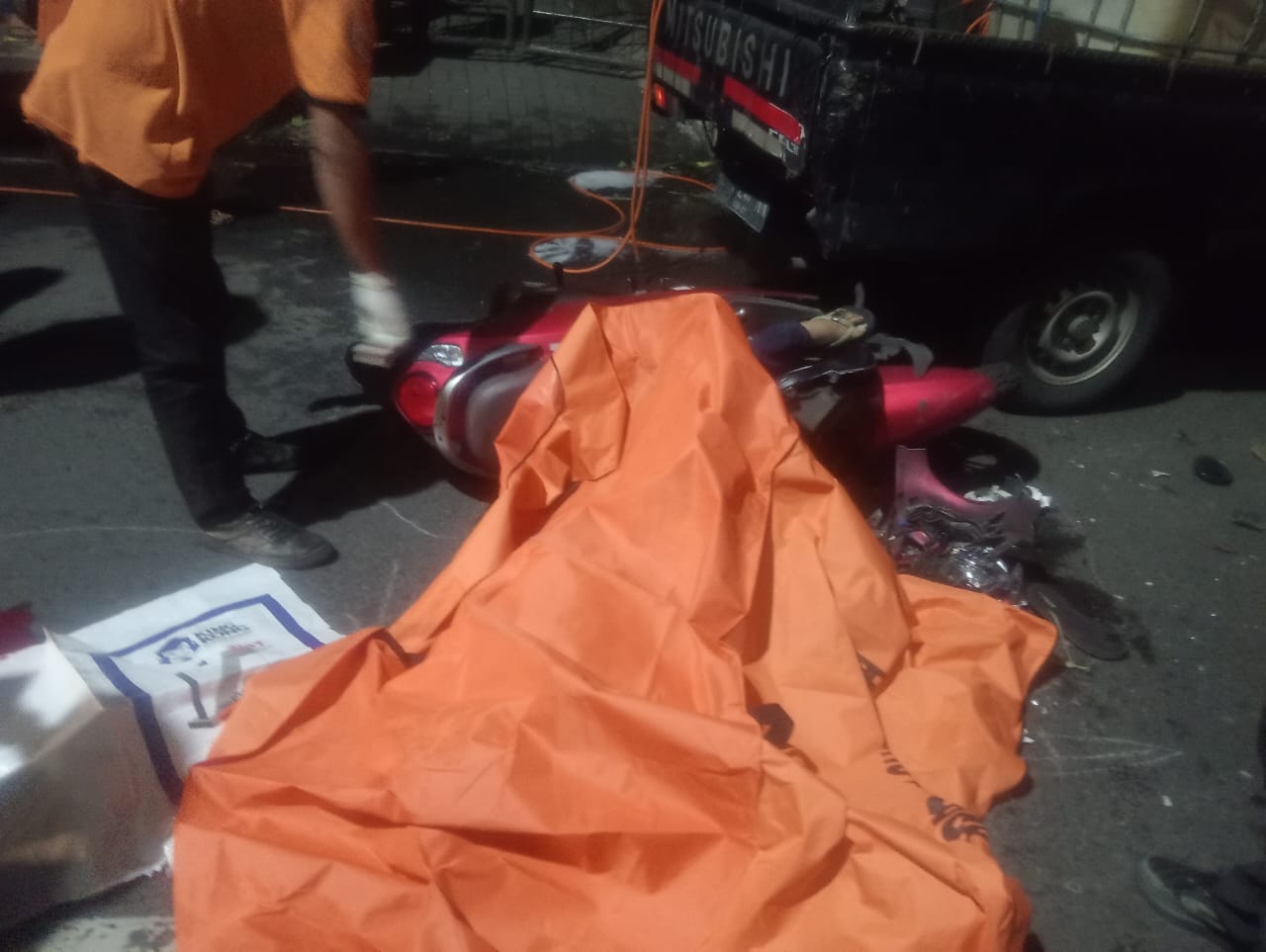 NAHAS : Petugas mengevakuasi pengendara motor yang meninggal dunia usai menabrak pikap parkir di Jalan Stasiun Wonokromo, Surabaya, Rabu (17/12).(IST/RADAR SURABAYA)