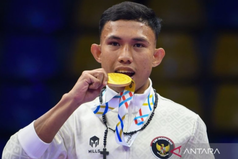 Riyan Jefri Hamonangan Lumbanbatu menggigit medali emasnya usai mengalahkan petarung Thailand Jakkrit Kongtook dalam babak final nomor K-1 60 kilogram putra cabang Kickboxing SEA Games 2025.
