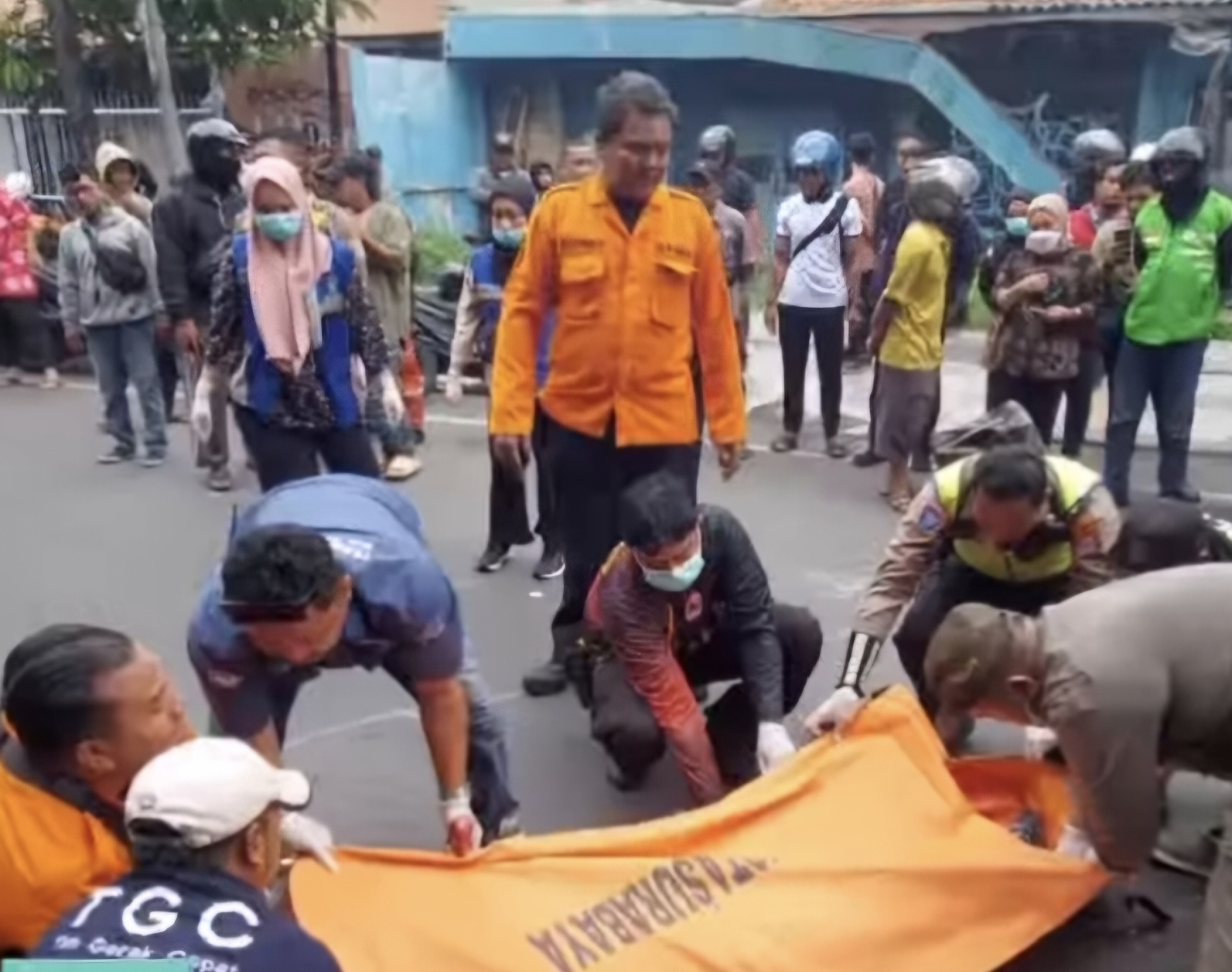 EVAKUASI: Jasad pengendara motor yang meninggal dunia usai terlibat kecelakaan terlindas truk trailer di Jalan Perak Timur, Surabaya. (IST/RADAR SURABAYA)
