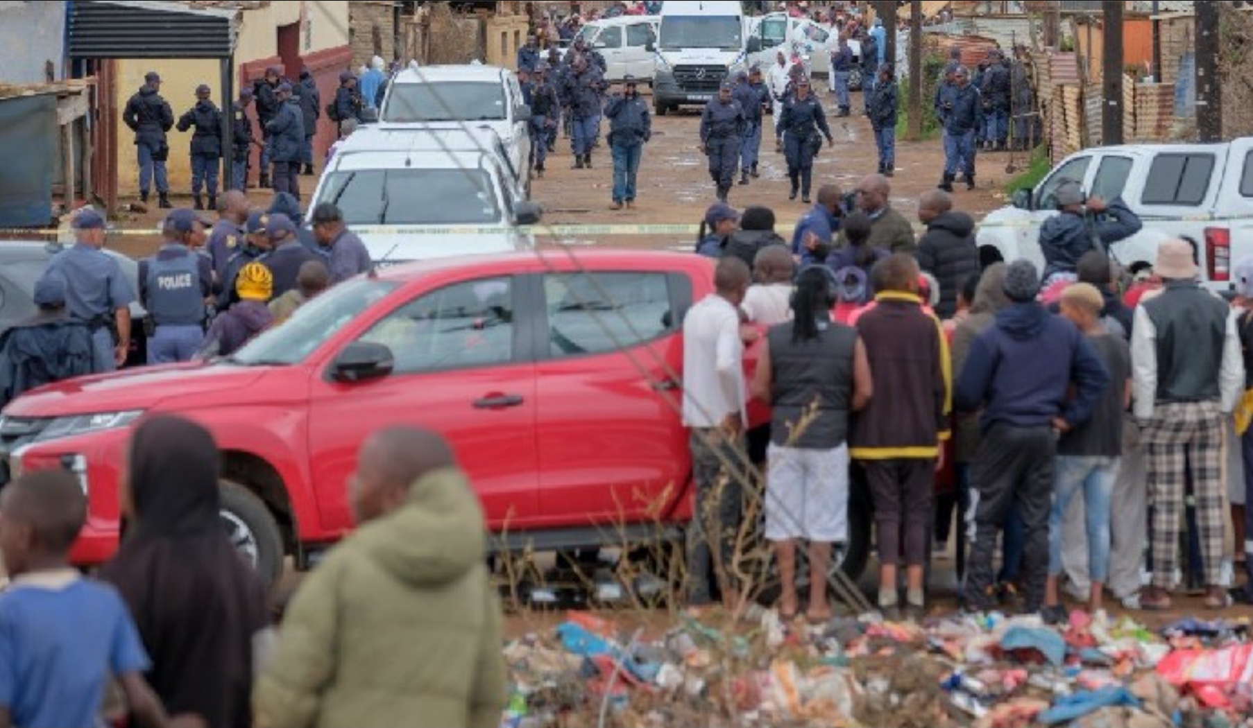 Warga menyaksikan polisi yang melakukan pemeriksaan di lokasi penembakan massal di Bekkersdal, Johannesburg.
