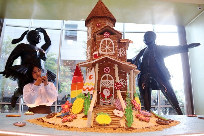 RUMAH KUE JAHE: Pengunjung berswa foto dengan miniatur rumah pantai, yang dibuat dari kepingan kue jahe setinggi 120 sentimeter, di lobi Hotel Ciputra World Surabaya, Minggu (21/12).
