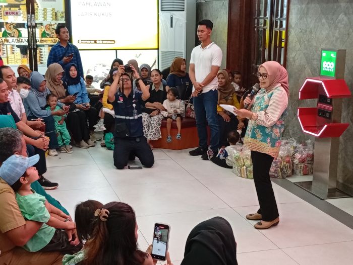PESAN: Rini Indriyani (kanan) bersama anak-anak dan orang tua di stasiun Surabaya Gubeng lama untuk mengenalkan kereta api commuter line, Selasa (23/12).