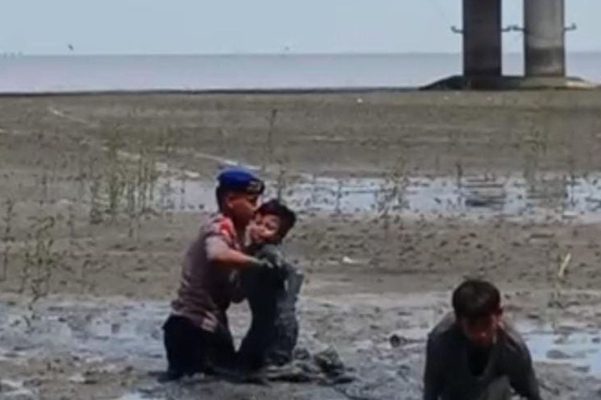 Personel Ditpolairud Polda Jatim saat menyelamatkan anak yang terjebak lumpur di pantai Kenjeran, Surabaya.