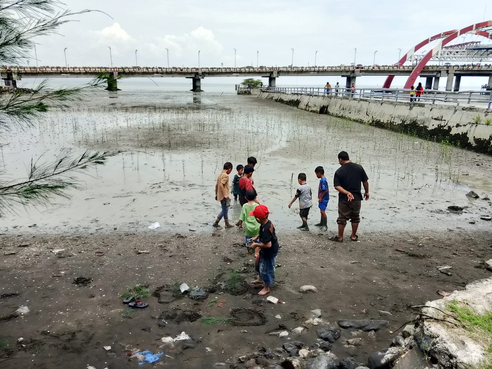 LIBURAN: Pengunjung THP Kenjeran bermain lumpur yang mengendap di pinggir pantai. (ESTU FARIDA LESTARI/JAWA POS)