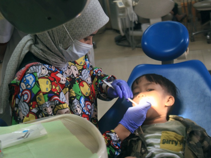 PERIKSA: Seorang dokter gigi memeriksa kondisi salah satu pasiennya yang masuk kategori anak-anak .