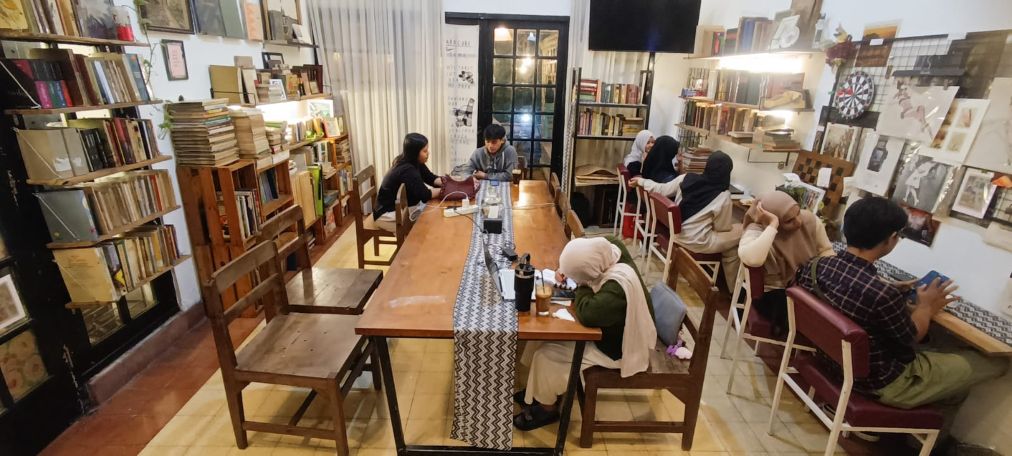 KAFE PERPUSTAKAAN: Delina, salah satu pengunjung yang merupakan mahasiswa membaca koleksi buku, di Damai Studio, Surabaya, Kamis (8/1).