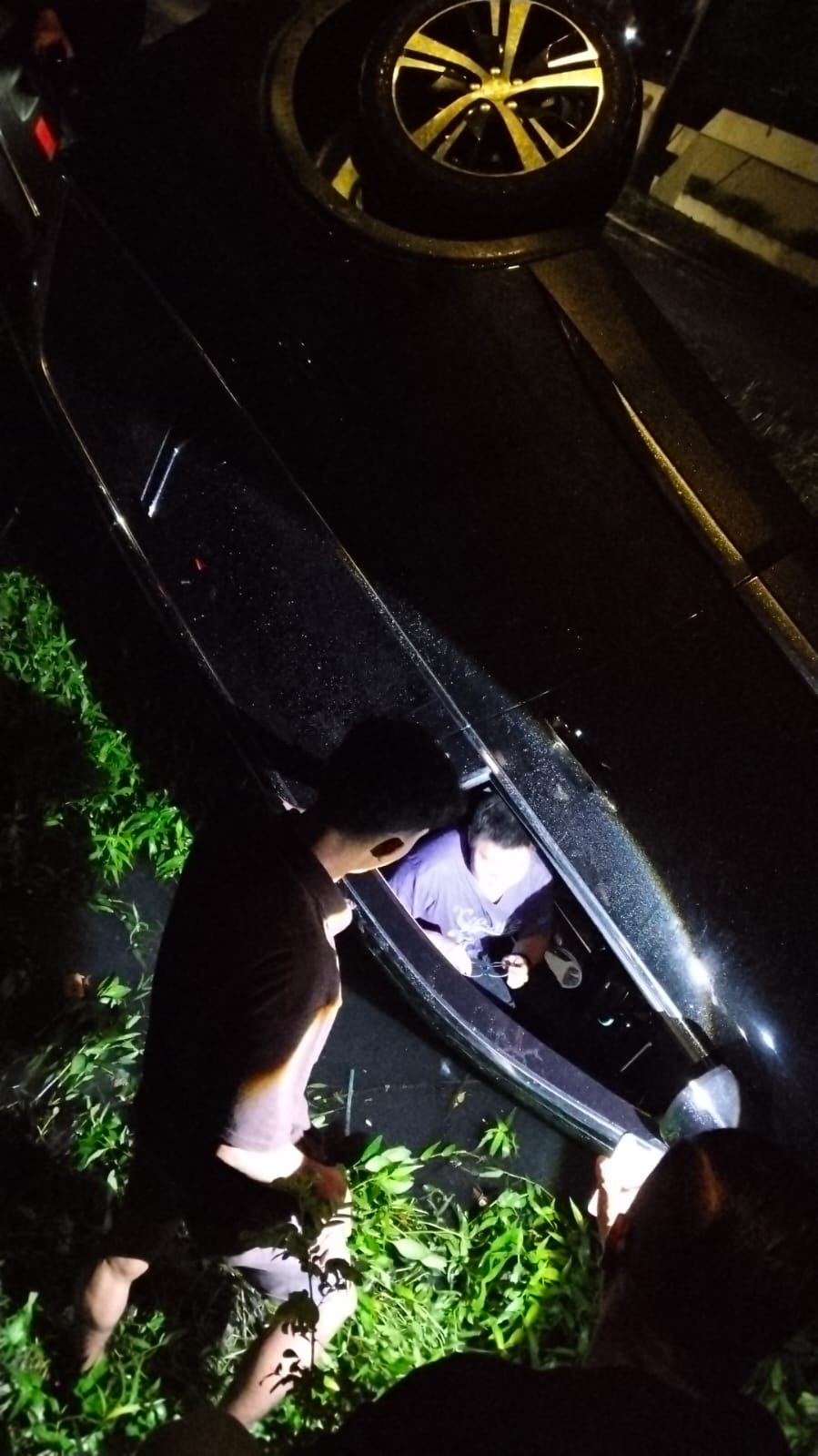 PENYELAMATAN: Warga membantu pengemudi mobil saat tercebur di sungai Jalan Dharmahusada Indah, Surabaya. (IST/RADAR SURABAYA)