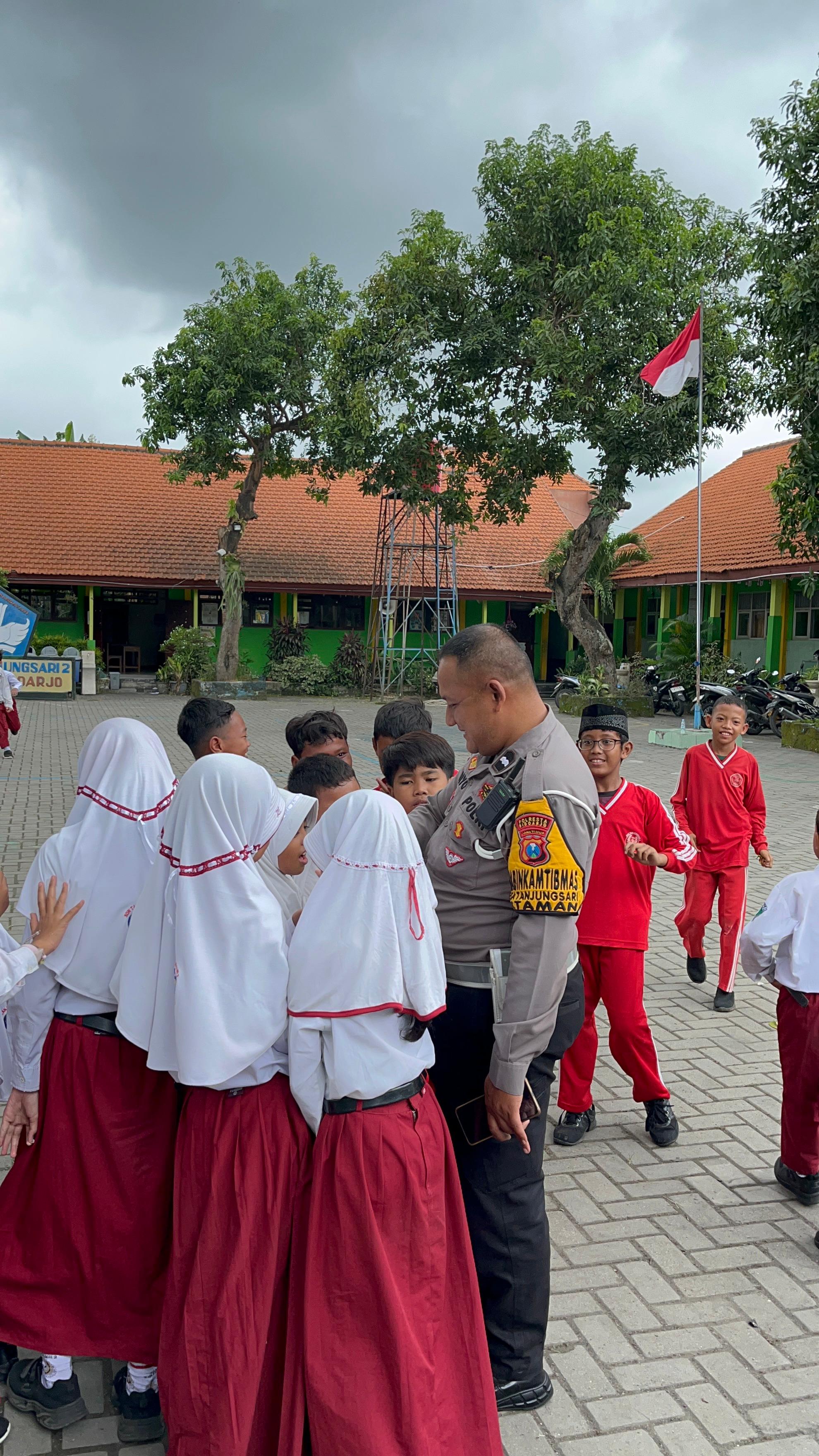 RAMAH: Bhabinkamtibmas Polsek Taman Aipda Dwi saat bercengkerama dengan siswa SDN Tanjungsari 2, Sidoarjo. Ia mensosialisasikan bahaya bullying dan gadget.(IST/RADAR SURABAYA)