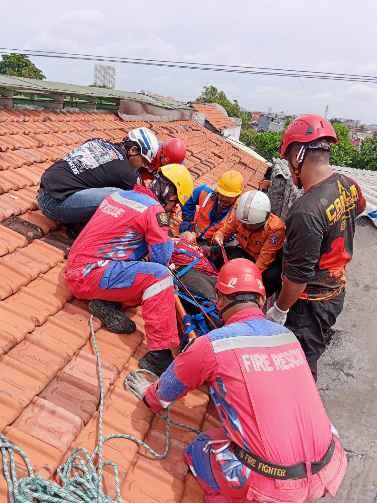 PINGSAN : Tim Rescue DPKP Surabaya mengevakuasi ARS tukang yang tersengat listrik di atap rumah kos Jalan Banyu Urip, Surabaya, Rabu (14/1). (IST/RADAR SURABAYA)
