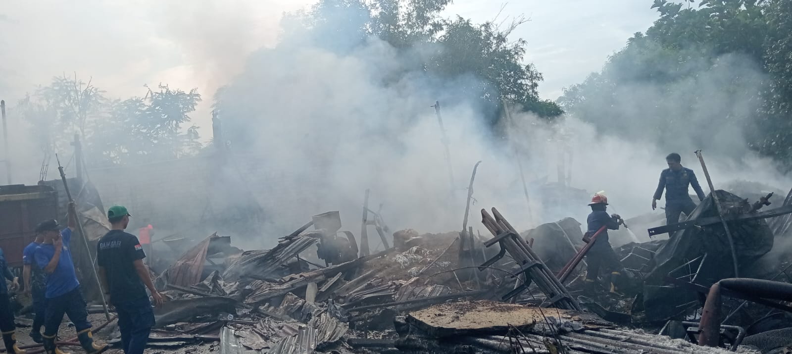 HABIS: Petugas berusaha memadamkan api saat kebakaran gudang pakan ternak di Prambon, Sidoarjo. (IST/RADAR SURABAYA)
