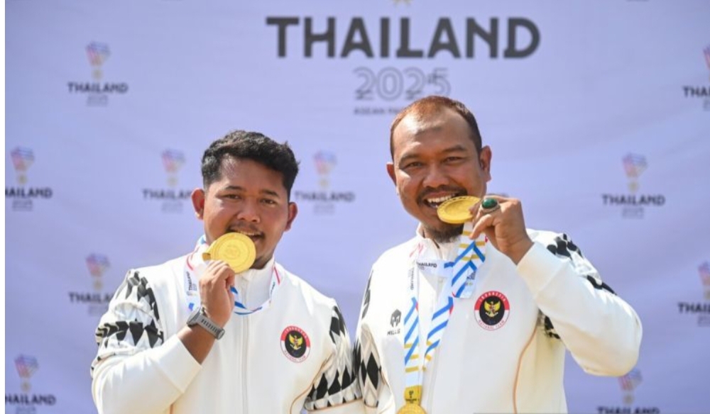 Pemanah Indonesia Setiawan (kiri) dan Kholidin (kanan) menggigit medali emas saat penganugerahan medali recurve ganda putra terbuka ASEAN Para Games 2025 Thailand di Wongchavalitkul University.