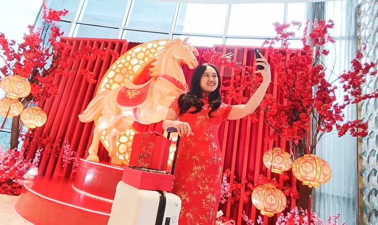 SAMBUT IMLEK: Salah satu tamu Hotel Ciputra World Surabaya, berawal foto dengan latar belakang dekorasi kuda api bernuansa merah, yang dipajang di lobi hotel untuk menyambut perayaan Imlek 2026.