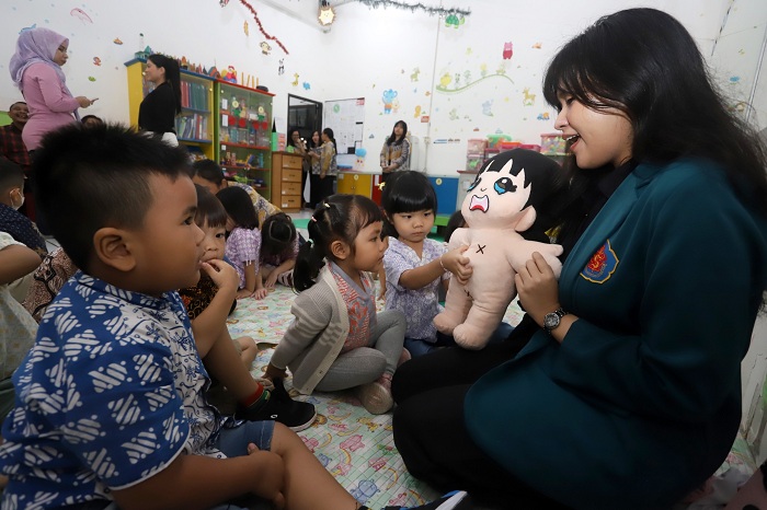 BONEKA PENDIDIKAN: Amelia Margaretha Suprapto, mahasiswa FIK Ubaya, mengajarkan terkait area-area vital yang tidak boleh disentuh oleh orang lain, dengan menggunakan boneka peraga, di kampus setempat.