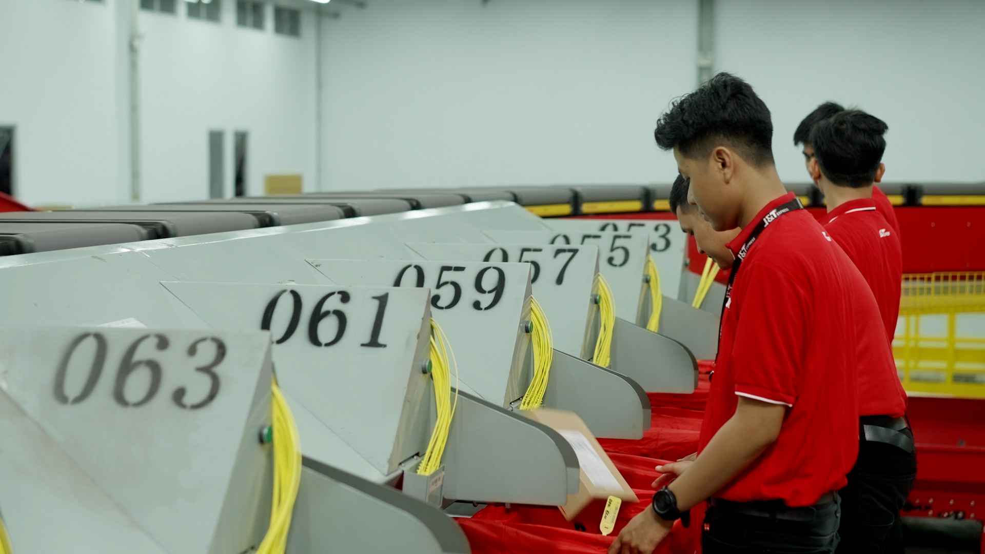 Pekerja J&T Express sedang melakukan penyortiran paket dengan bantuan mesin conveyor.