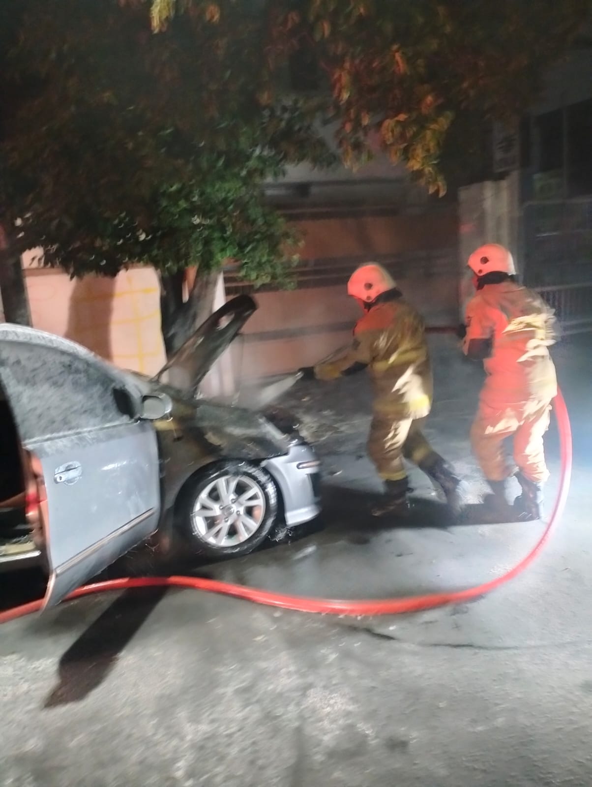 Petugas Damkar memadamkan mobil milik warga Jalan Karanggayam yang terbakar di Jalan Jemursari, Wonocolo, Surabaya.