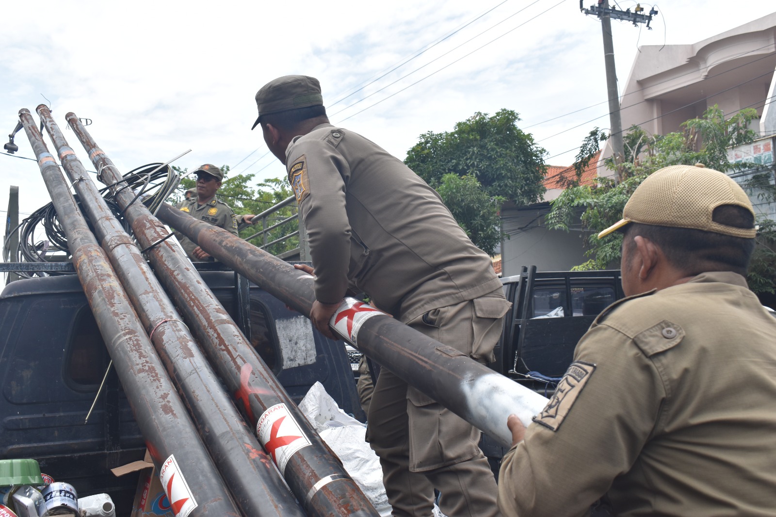 Petugas gabungan dari Satpol PP dan DSDABM Surabaya menertibkan tiang kabel fiber optik ilegal.