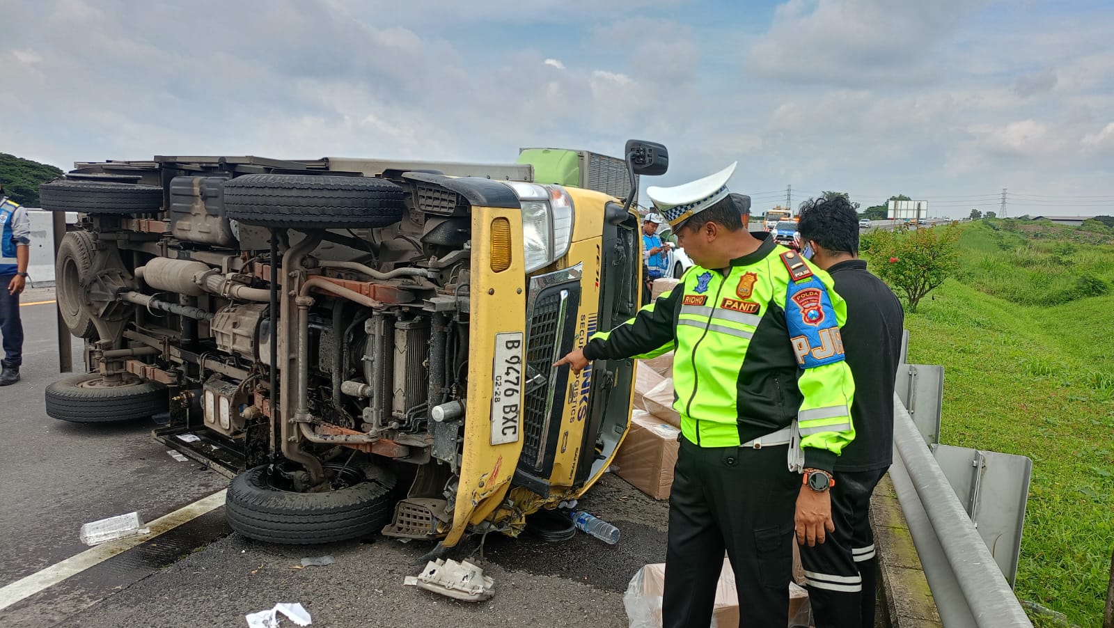 PENANGANAN: Kondisi truk boks saat terguling di Tol Sumo, Warugunung, Surabaya.(IST/RADAR SURABAYA)