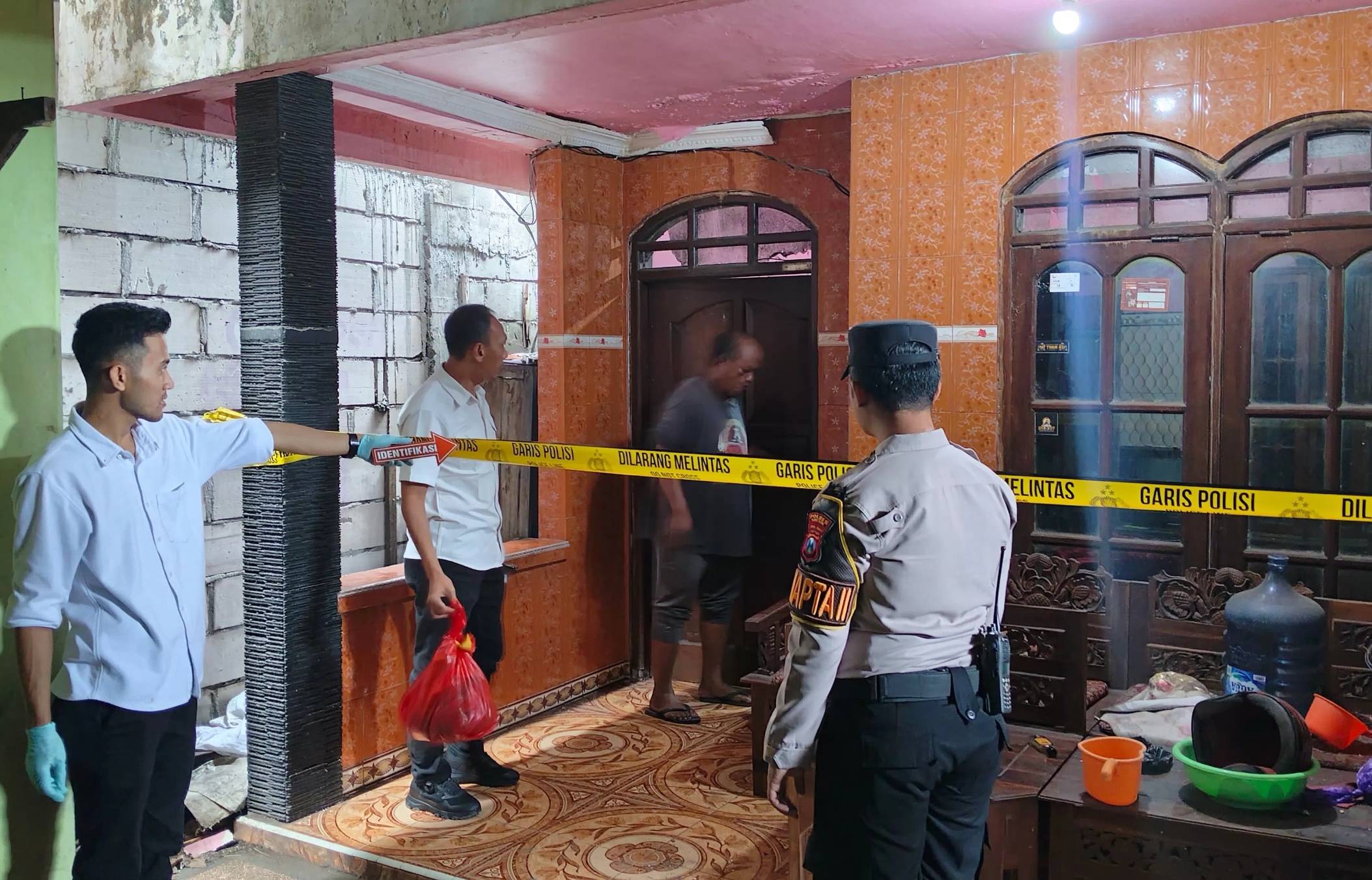 Anggota Polsek Kebomas melakukan olah TKP di rumah korban pengakhiran nyawa di Jalan Dr. Wahidin Sudirohusodo, Kembangan, Kebomas, Gresik.