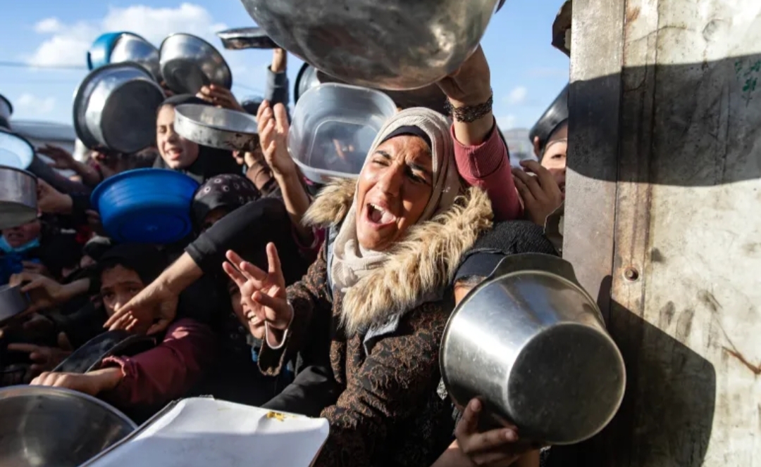 Warga Palestina yang mengungsi berebut hidangan berbuka puasa (iftar) yang dibagikan oleh dapur amal selama bulan suci Ramadan di Khan Younis, Jalur Gaza bagian selatan. 
