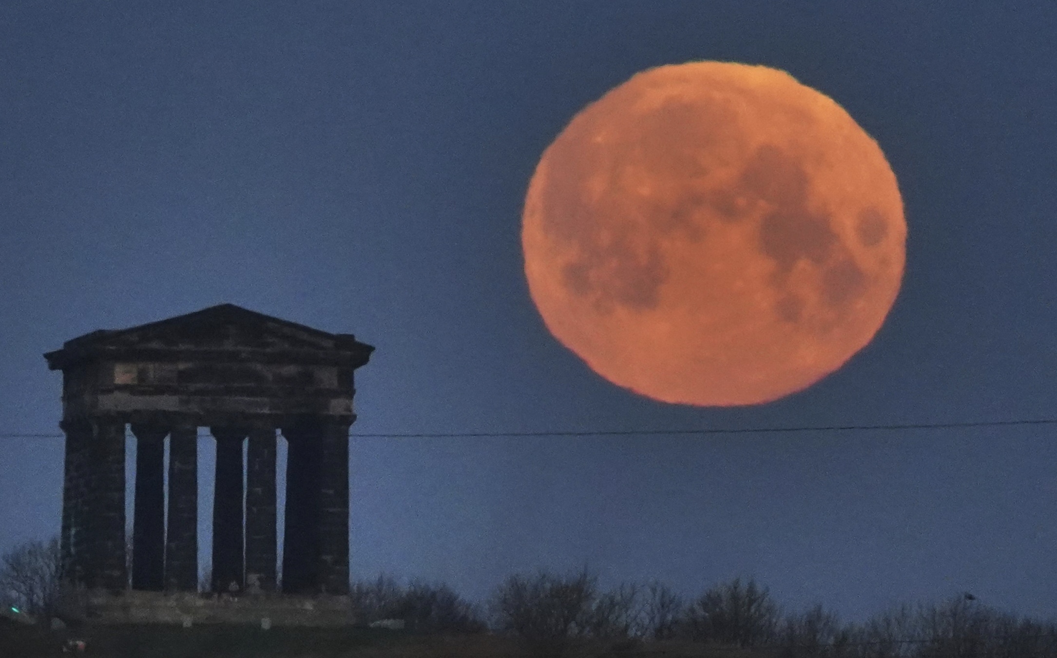 Penampakan bulan merah terbenam di balik Monumen Penshaw, dekat Sunderland, Inggris, Selasa (3/3).