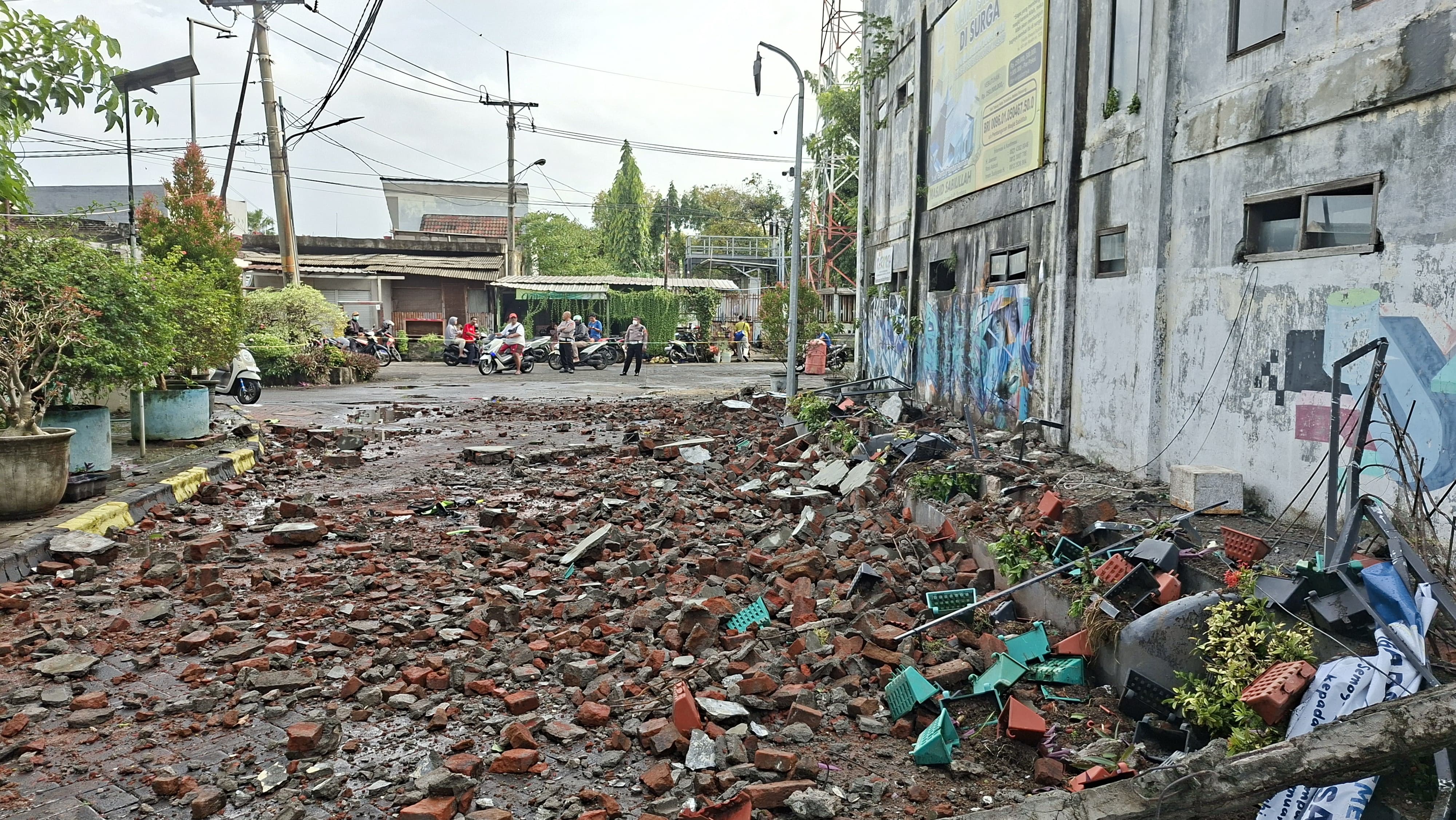 RERUNTUHAN: Lokasi pengendara motor yang tertimpa tembok di Jalan Kebraon Indah Permai, Surabaya. Korban dinyatakan meninggal dunia usai dirawat.(MAHRUS/RADAR SURABAYA)