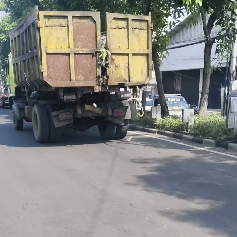 Truk sampah viral dengan penutup bak tak tertutup rapat membuat sampah berceceran di jalan.