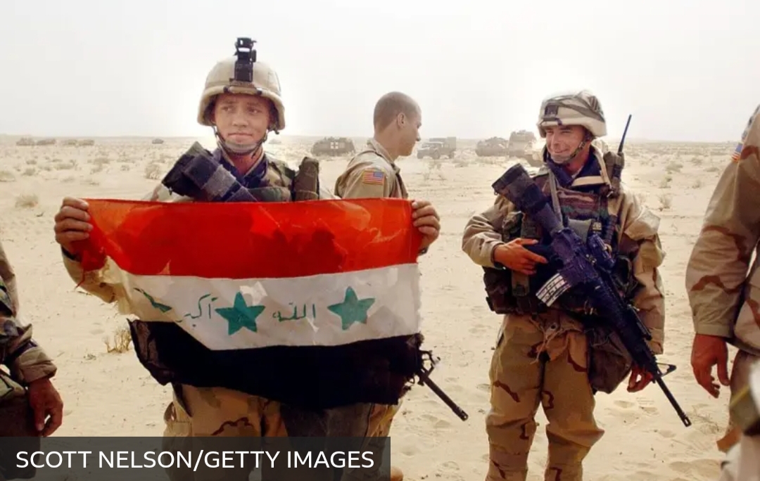 Tentara AS memamerkan bendera Irak saat invasi militer 2003 silam. 