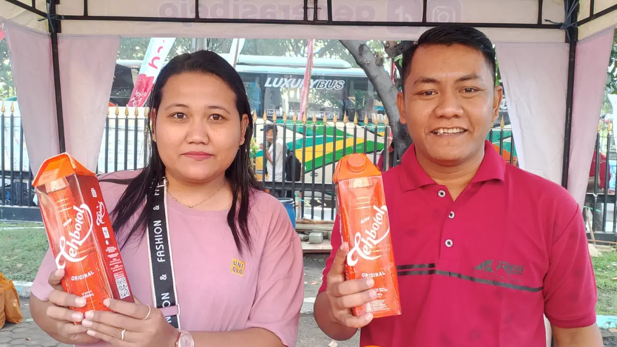 
KESEGARAN SOSRO TEMANI PERJALANAN: Dua peserta Mudik Gratis Radar Surabaya 2026 menunjukan Tehbotol Sosro kemasan kotak dengan volume 1.000 ml yang mereka terima sebelum berangkat.