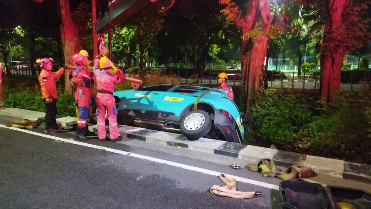 LAKA TUNGGAL: Tim Rescue DPKP Surabaya mengevakuasi mobil taksi listrik yang disopiri Eko terperosok di saluran air Jalan Ahmad Yani, Surabaya, Senin (30/3) dini hari. (ISTIMEWA)