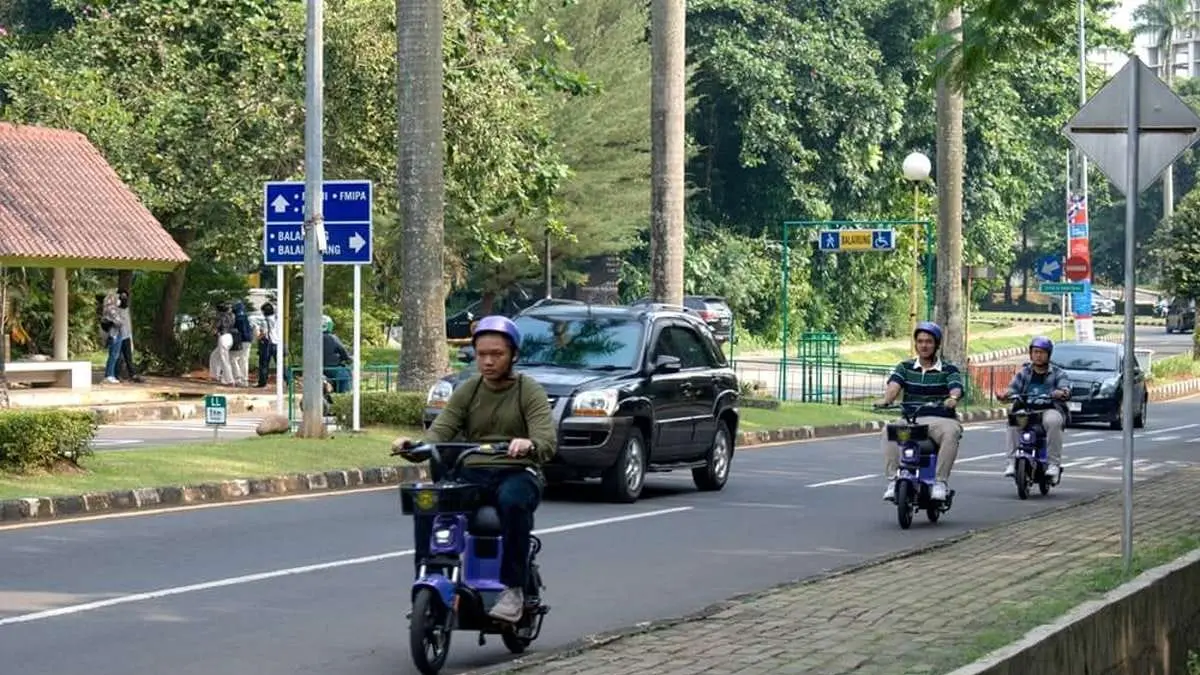 Waspada : Pengendara sepeda listrik melintas di jalan raya bersama kendaraan bermotor di Surabaya.