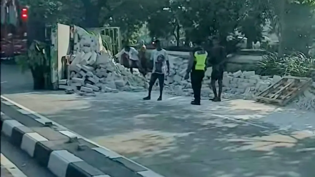 EVAKUASI: Truk bermuatan bata ringan yang terguling di Jalan Kedung Cowek, Surabaya, saat proses evakuasi.(IST/RADAR SURABAYA)