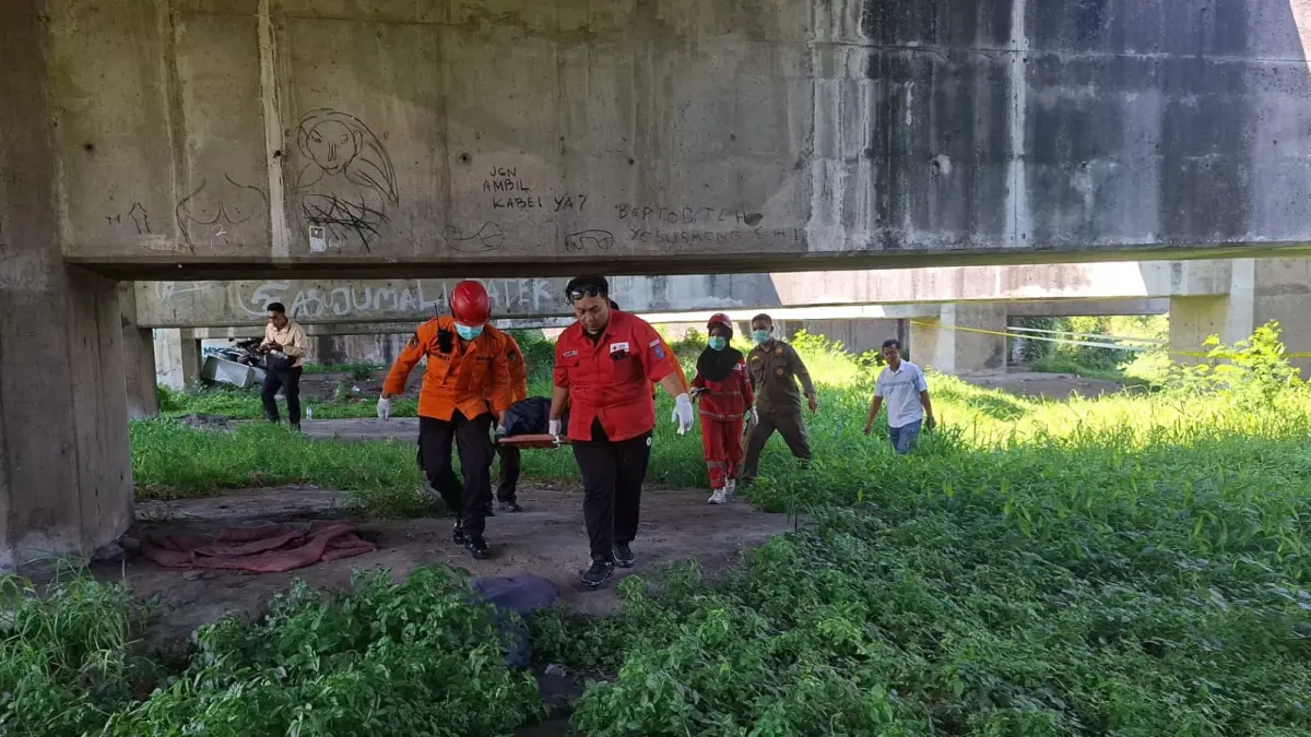 EVAKUASI: Petugas membawa jenazah korban tewas di bawah tol Waru-Juanda, Siwalankerto, Surabaya. Korban diketahui warga Bratang Gede II, Surabaya. (MAHRUS/RADAR SURABAYA)