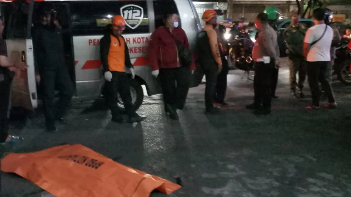 NAHAS: Petugas menutupi mayat korban JK penyeberang jalan yang meninggal dunia tertabrak motor di Jalan Undaan Kulon, Surabaya Minggu (19/4) malam. (ISTIMEWA)