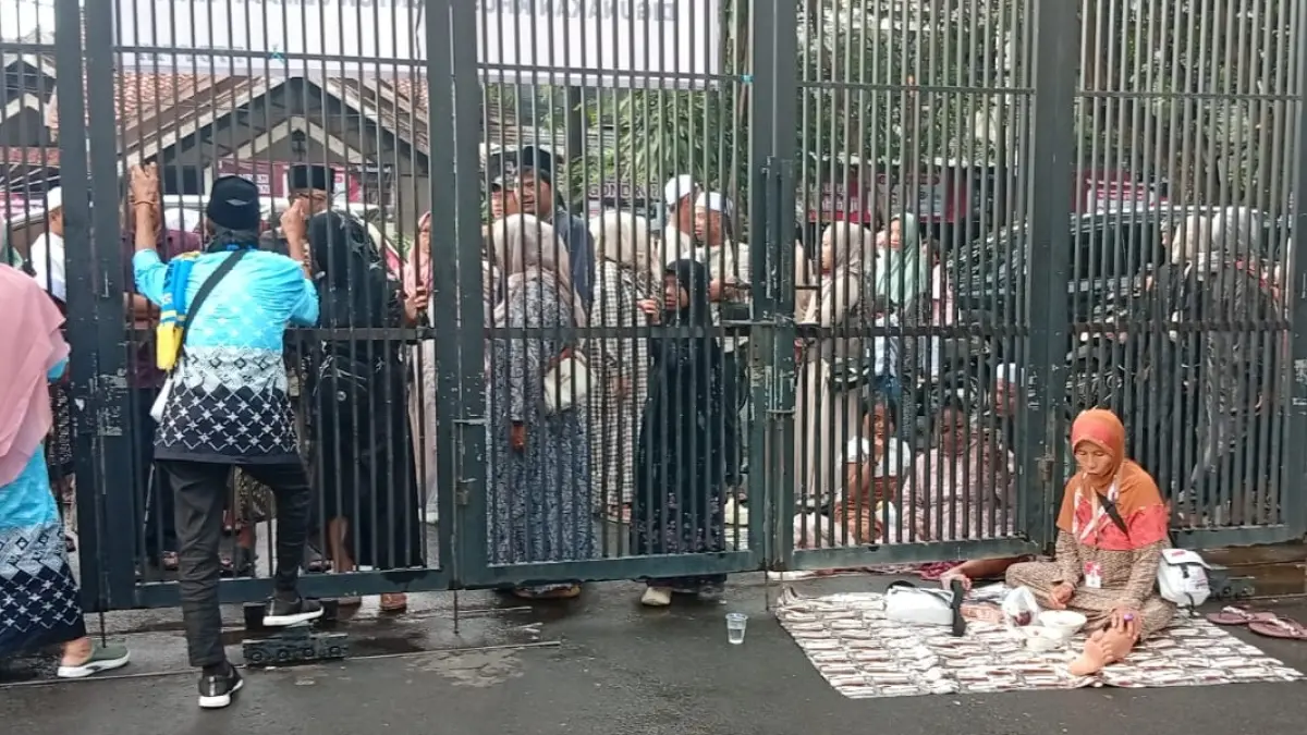 Jemaah haji saat menikmati makanan dari luar sembari bercengkrama dengan keluarga dibalik pagar pembatas Asrama Haji Surabaya. (Rahmat Sudrajat/Radar Surabaya)