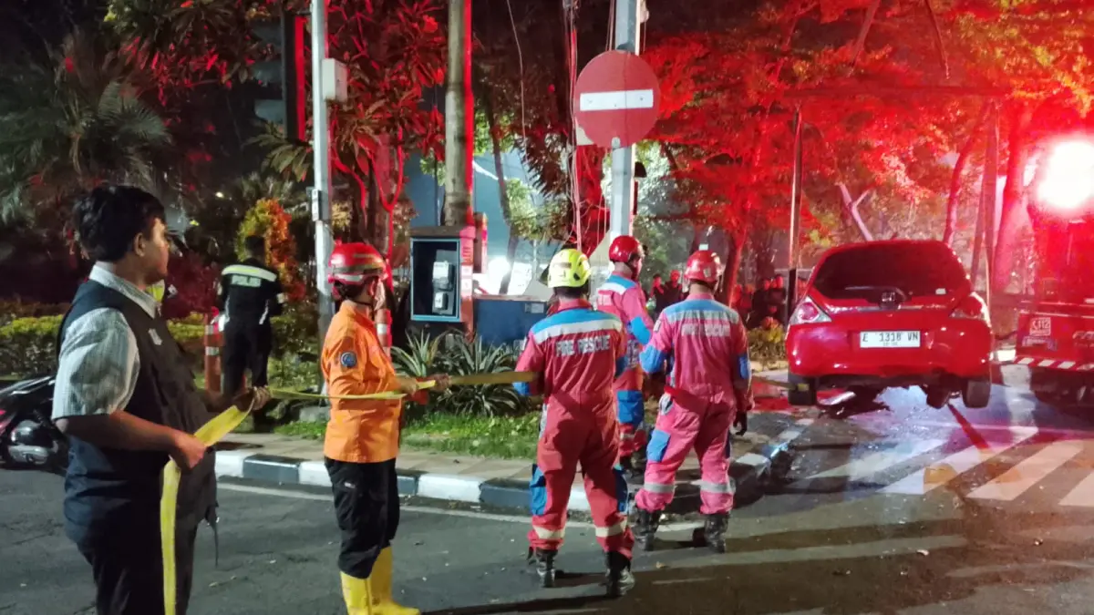 EVAKUASI: Petugas saat mengevakuasi mobil yang menabrak trotoar dan TL hingga roboh di Jalan Diponegoro, Surabaya. (IST/RADAR SURABAYA)